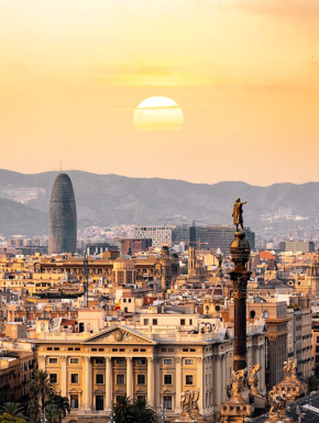 Luchtfotografie van de stad Barcelona met de ondergaande zon op de achtergrond.
