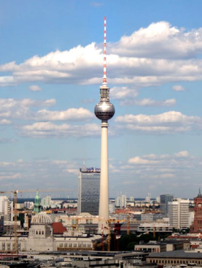 Afbeeling van de tv-toren in Berlijn in Duitsland met een blauwe lucht en stapelwolken op de achtergrond.