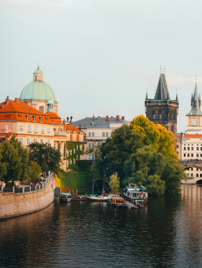 Afbeelding van een rivier met daarnaast gekleurde gebouwen en een stenen brug.