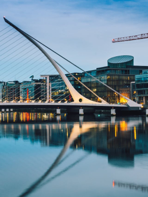 Foto van een witte, betonnen brug in Dublin met op de achtergrond moderne gebouwen