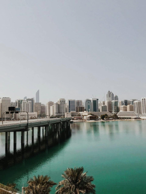 Afbeelding van groenblauw water met een brug eroverheen die leidt naar moderne witte gebouwen.